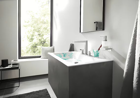 Chromovaný nástěnný dávkovač tekutého mýdla hansgrohe AddStoris se skleněnou nádobou a kovovým držákem.