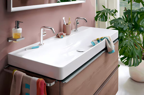 Chromovaný nástěnný dávkovač tekutého mýdla hansgrohe AddStoris se skleněnou nádobou a kovovým držákem.