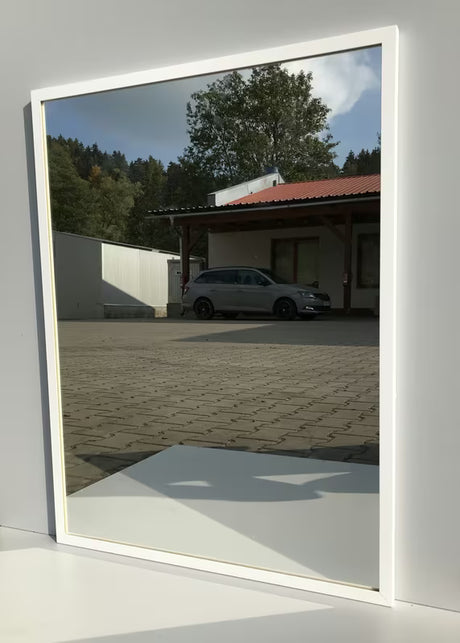 Koupelnové zrcadlo s bílým hliníkovým rámem, vhodné pro svislé i vodorovné zavěšení, 60 x 80 cm.