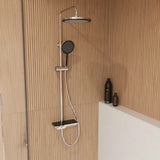 Sprchový systém SAT s termostatickou baterií, hlavovou a ruční sprchou a skleněnou poličkou v černé a chromové barvě.