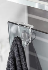 Transparentní háček SAT Walk-In pro zavěšení na skleněnou hranu sprchové zástěny bez vrtání.